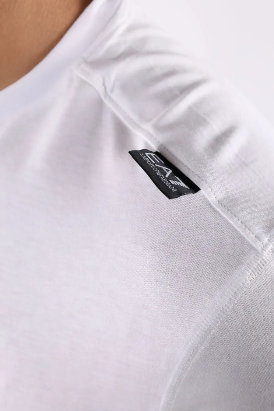 Camiseta blanca con maxilogo plateado detrás
